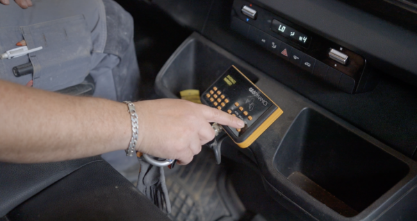 Arbeider die in een bedrijfswagen zijn badge scant op een ingebouwde badgelezer